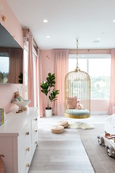 a bedroom with pink walls and curtains, a birdcage hanging from the ceiling