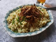 a bowl filled with pasta and meat on top of a white table cloth next to a spoon