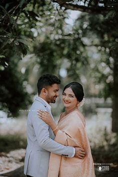 a man and woman standing next to each other under a tree