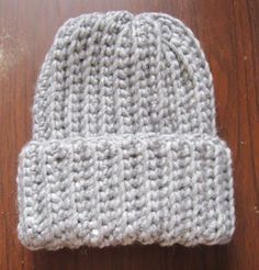 a gray knitted hat sitting on top of a wooden floor next to a pair of scissors