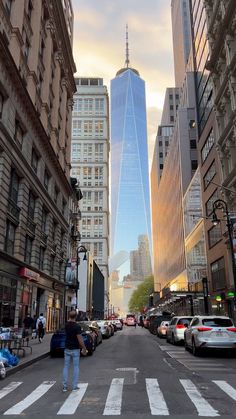 a man is walking down the street in front of tall buildings with skyscrapers on either side