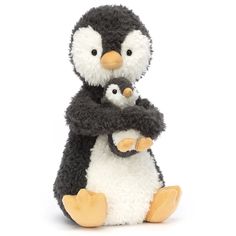 two stuffed penguins are sitting next to each other on a white background and one is holding another penguin