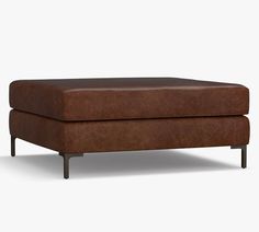 a brown ottoman sitting on top of a white floor