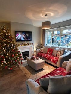 a living room filled with furniture and a christmas tree in front of a tv mounted on the wall