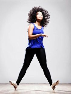 a woman in blue shirt and black pants dancing