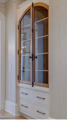 a large white cabinet with glass doors in a room next to a door and window