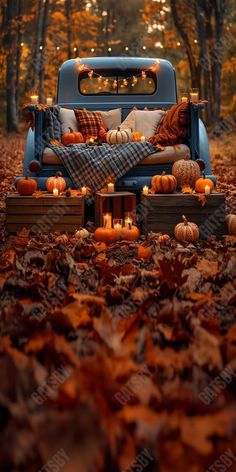 an old truck with pumpkins and candles in the bed is surrounded by fall leaves