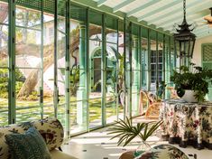 the inside of a house with lots of windows and plants on the table in front of it