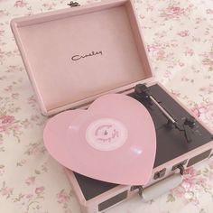 a pink record player sitting on top of a table next to a case with the lid open