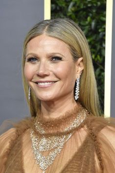 an image of a woman smiling at the camera with her hair in a ponytail and wearing large earrings