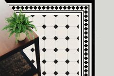 a potted plant sitting on top of a wooden table next to a black and white tiled floor