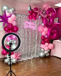 pink and silver balloons are on display in front of a backdrop