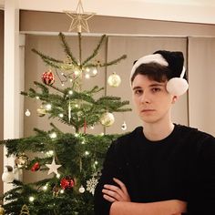 a young man standing in front of a christmas tree