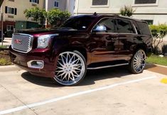 a maroon suv parked in a parking lot next to a building with white rims