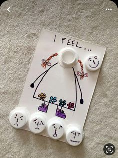 a white piece of paper that has some buttons attached to it with faces drawn on it