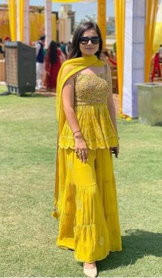 a woman in a yellow dress standing on the grass