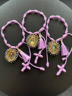 four bracelets with beads and tassels on top of a black tablecloth