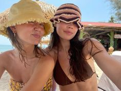 two women in bikinis and hats on the beach