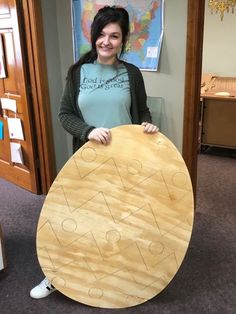 a woman holding a large wooden board with letters and numbers on it in an office