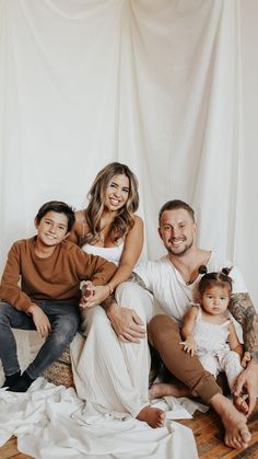 a man, woman and two children are posing for a family photo in front of a white backdrop