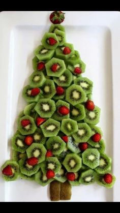 a christmas tree made out of kiwis and strawberries on a white plate