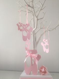 there is a tree that has pink decorations hanging from it's branches and baby shoes