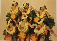 a group of women in hula skirts posing for a photo with flowers on their heads