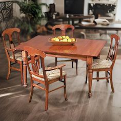 a wooden table with chairs around it and fruit on the plate at the end of the table