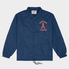 Through the late 1960s and '70s, football coaching staffs transitioned their sideline wardrobes from full suits and ties to light, workmen-style jackets; these coaches jackets were predecessors to the more spirited, uniformly branded looks we see on the sidelines today. Our take on an Auburn coaches jacket matches era-appropriate typefaces and logos with the structured collar and boxy fit of a vintage jacket. Made with durable-yet-lightweight nylon, and high-quality snap plackets and drawcords, Vintage Fall Outerwear For Sports Events, Navy Collegiate Outerwear For Sports Events, Classic Long-sleeve Outerwear For Sports Events, Classic Long Sleeve Outerwear For Sports Events, Classic Sport Coat For Fall, Classic Sport Coat For Fall Sports, Varsity Fan Gear Outerwear For Fall, Team-colored Fall Outerwear For Fan Gear, Fall Varsity Outerwear For Fan Gear