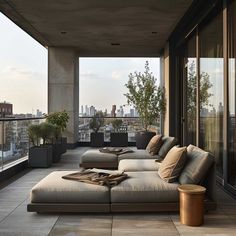 a large couch sitting on top of a wooden floor next to a tall glass window