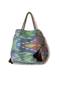 Ikat bag made with hand-woven silk ikat fabric. The side tassels help adjust the upper width of the bag. You can pull the tassels to make the bag look narrower or let it out to make it wider. The lining is made of traditional hand-made striped bekasam fabric. Inner pockets, one with zipper. Snap magnetic closure. Handles are made of hand-woven bands. This bag is a unique addition to your outfit. Match it with our ikat kaftans or contemporary outfits. Upper Width: 50cm (20”) Lower Width: 30cm (12 Tassel Double Handle Bag, Daily Use Double Handle Bags With Tassels, Daily Use Double Handle Tassel Bags, Daily Use Shoulder Bag With Tassels And Double Handle, Daily Use Double Handle Tassel Shoulder Bag, Daily Use Double Handle Shoulder Bag With Tassels, Blue Bags With Tassels For Vacation, Daily Double Handle Shoulder Bag With Tassels, Travel Tassel Shoulder Tote Bag