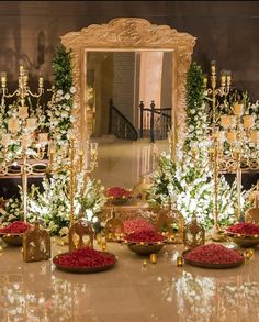 a room filled with lots of tables covered in flowers and gold plates on top of them