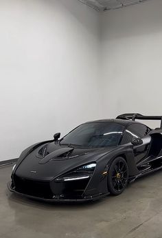 a black sports car parked in a large room with no one around it on the floor