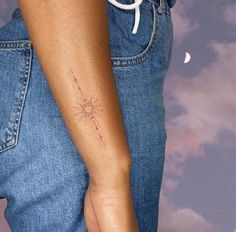 a woman's arm with a small sun tattoo on the left side of her right arm