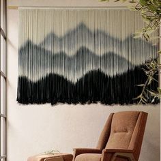 a chair and ottoman in front of a wall hanging