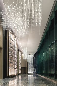 an elegant hallway with chandeliers and glass walls in the background, is lit by lights that are suspended from the ceiling