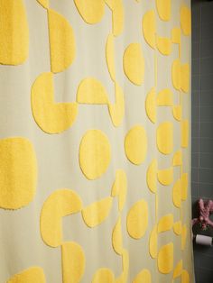 a yellow and white shower curtain with circles on it in a gray tiled bath room