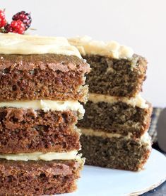 a slice of cake with white frosting and raspberries on top is sitting next to the rest of the cake