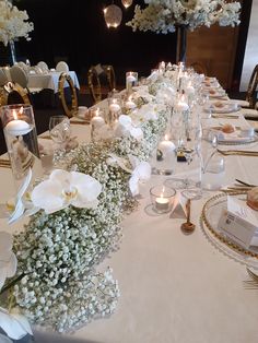 a long table is set with white flowers and candles for an elegant dinner or reception