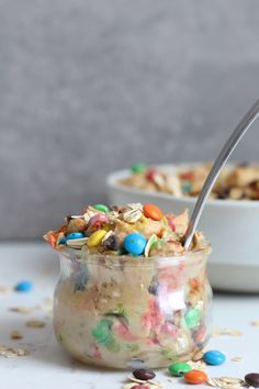 a bowl full of cereal with a spoon in it next to another bowl filled with cereal