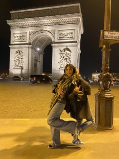 a woman is posing in front of the arc de trio porte at night with her hand on her hip