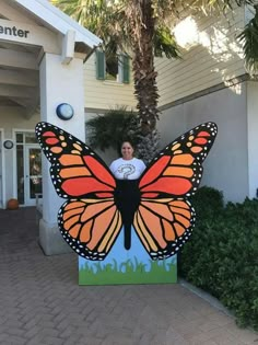 a woman standing in front of a giant butterfly