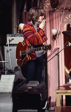 a man standing in front of a microphone holding a guitar