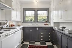 a kitchen with black and white checkered flooring, cabinets, stove top oven and sink