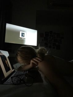 a woman is laying in bed with her head on the computer keyboard and looking at the screen