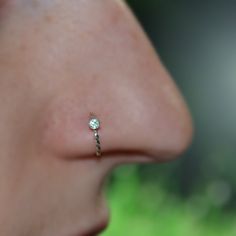 a woman's nose with a tiny diamond ring on top of her nose and behind her ear