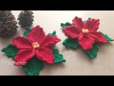 crocheted poinsettis and pine cones are on the table next to each other