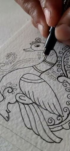 a person is drawing on paper with a pen in their hand and it looks like an intricate bird