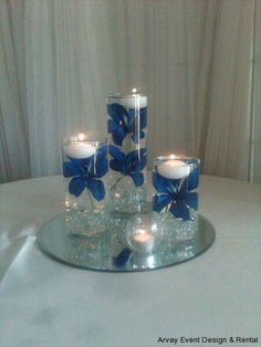 blue flowers and candles are arranged on a table