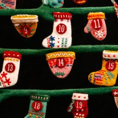 christmas stockings and mittens are hanging on a green shelf in front of a black background